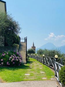 a path with flowers and a fence with a church in the background at WELCOME TRAVELLER Charm Montees Apartment in Brenzone sul Garda +5 photos