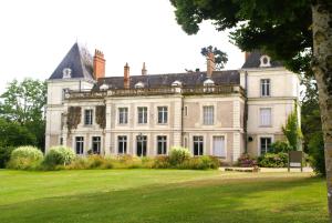 ein großes weißes Haus mit einer Statue darüber in der Unterkunft Le Relais du Golf- Château de la Touche in Ballan-Miré