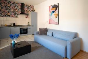 a living room with a blue couch and a kitchen at Blauwal - W14, Zentral in Bahnhofsnähe, Balkon, Küche in Ulm +4 photos