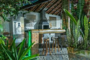 an outdoor kitchen with a stove and stools at Cantim da Praia natureza integrada in Praia Grande