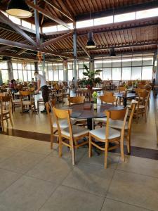 ein Restaurant mit Holztischen und Stühlen und einem Mann im Hintergrund in der Unterkunft Portal de Gravatá para até 6 pessoas - Térreo in Gravatá