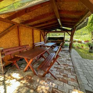 a group of wooden benches sitting under a pavilion at Vila Milena in Međuvršje