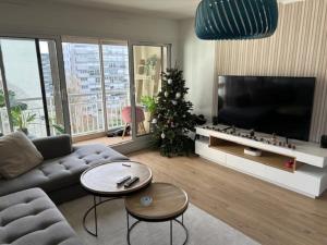 ein Wohnzimmer mit einer Couch und einem Weihnachtsbaum in der Unterkunft Bel appartement familial proche Versailles in Vélizy-Villacoublay