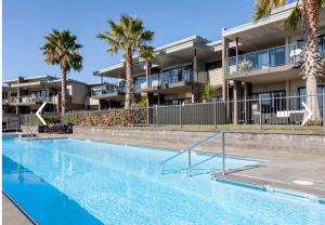 a swimming pool in front of a building with palm trees at Bliss Out on The Waterways in Whitianga