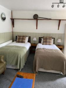 una habitación con dos camas y una silla y dos mesas en The Bothy at Christmas Cottage, en Rowardennan