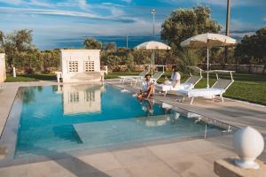 two people sitting on chairs next to a swimming pool at Parco Del Vecchio in Savelletri di Fasano
