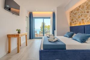 Un dormitorio con una cama y un escritorio y una ventana. en Alex Boutique Hotel, en Himare