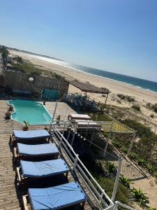 a group of lounge chairs and a pool on the beach at Lehani Beach Hostel in Praia do Tofo +47 photos