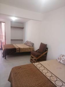 ein Zimmer mit 3 Betten und einem Stuhl darin in der Unterkunft Casa Ixtapa in Ixtapa