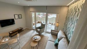 Una sala de estar con un sofá y un televisor. en Apartamentos Paseo Colón, en Foz