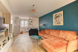 Una sala de estar con un sofá y una pared azul. en Charmante maison - Proche JO 2024, en Montigny-le-Bretonneux