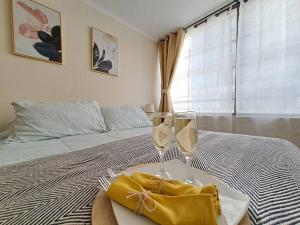 two glasses of wine on a table in a bedroom at Bellavista Cozy Apartment in Santiago