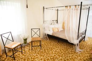 a bedroom with a canopy bed and a chair at Smuku Muiža in Remte