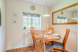 a dining room with a wooden table and chairs at Beautiful Riverside Cottage with Large Garden, 2BR in Boldre