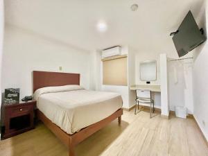 ein Schlafzimmer mit Bett, Schreibtisch und Fernseher in der Unterkunft HOTEL SALVADOR in Culiacán Rosales