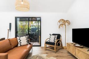 a living room with a couch and a flat screen tv at 3 Salty Sisters in Byron Bay