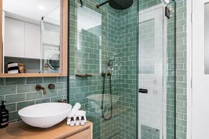 a bathroom with a sink and a shower with green tiles at 3 Salty Sisters in Byron Bay +24 photos
