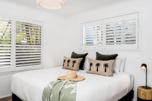 a white bedroom with a bed with a hat on it at 3 Salty Sisters in Byron Bay