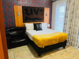 a bedroom with a bed and a black leather chair at Parow city -Star Legend Lodge in Cape Town