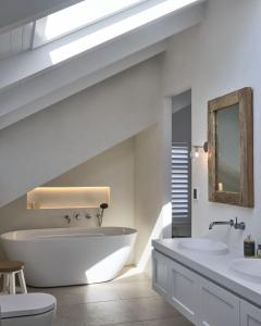 a bathroom with a large tub and two sinks at Bareena House by Beach Stays in Avalon