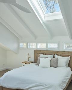 a bedroom with a white bed with a skylight at Bareena House by Beach Stays in Avalon