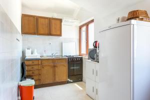 a kitchen with wooden cabinets and a white refrigerator at Apartments with parking space Supetar, Brac - 5670 in Supetar +30 photos
