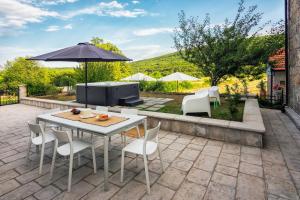 a patio with a table and chairs and an umbrella at Villa ''Stone Garden'' - Countryside with Heated Pool & Hot Tub in Trilj