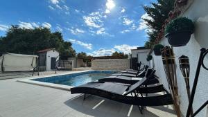 eine Gruppe von Stühlen neben einem Swimmingpool in der Unterkunft Family friendly apartments with a swimming pool Pula - 22040 in Pula