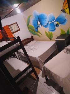 two beds in a room with a painting on the wall at Pousada Vida Mansa in Porto De Galinhas