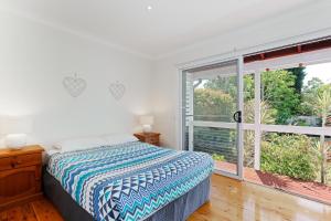 une chambre avec un lit et une grande fenêtre dans l'établissement Rubys Retreat, 44 Achilles Street - pet friendly, aircon, wifi & boat parking, à Shoal Bay