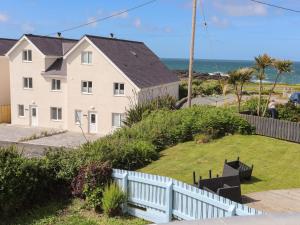 a house with a white fence and the ocean at Seaside Sanctuary in Holyhead