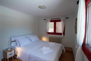 a bedroom with a white bed and a window at Oregano peaceful complex in Porto Rafti