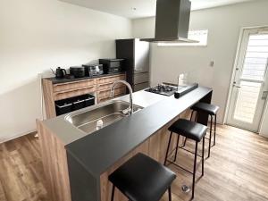 a kitchen with a sink and a counter with stools at Villa SUN58 ヴィラサンゴエイト in Miyako-jima