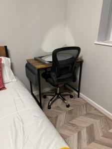 a desk with a black chair next to a bed at Comfy Studio Flat and Workspace near Ashton-U-Lyne Station in Stalybridge