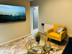 a living room with a yellow chair and a glass table at Comfy Studio Flat and Workspace near Ashton-U-Lyne Station in Stalybridge