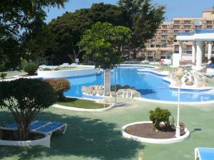 a large swimming pool in a resort with chairs and trees at Apartments Paraíso del Sur in Adeje