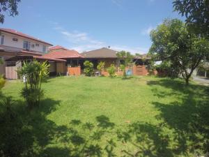 a yard with a green lawn in front of a house at Pan Sutera Homestay Comfortable Bali Experience in Alor Setar