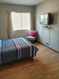 une chambre avec un lit, une chaise et une télévision dans l'établissement Bonito y Moderno 1 o 2 dormitorios, à Lima