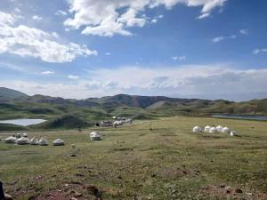 a field with domes in the middle of a mountain at Nice Yurt Camp in Sary-Mogul