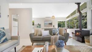 a living room with a couch and a fireplace at Casa Bianca - Pearl Beach in Pearl Beach