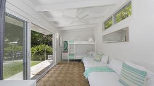 a living room with a white couch and windows at Casa Bianca - Pearl Beach in Pearl Beach