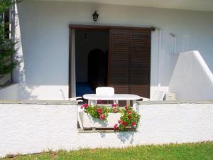 a patio with a table and flowers on a wall at Villa Anna Maria in Agia Paraskevi