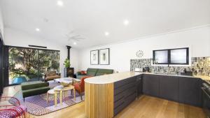 an open kitchen and living room with a large window at The Greenhouse - Pearl Beach in Pearl Beach