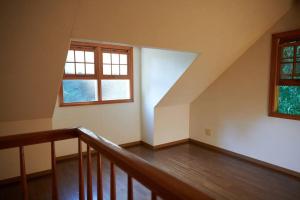 an attic room with a staircase and two windows at Parakeet Spa in Yufu
