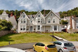 Deux voitures garées devant une grande maison dans l'établissement Sefton Court, à Llandudno