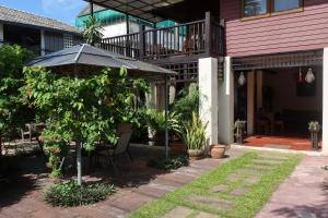 a house with an umbrella and a chair and a tree at Banjai Garden Guesthouse in Chiang Mai