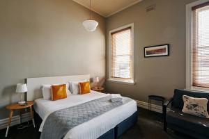 a bedroom with a bed with orange pillows and a chair at Healesville Hotel in Healesville