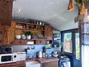 a kitchen with wooden cabinets and a white microwave at Travel Back in Time Fairy Cottage on the Cobbles an Experience Property in Haworth
