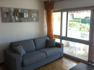 sala de estar con sofá azul y puerta corredera de cristal en Appartement Cap D'Agde, en Cap d'Agde