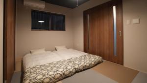 a small bedroom with a bed and a wooden door at HANASTAY花渓居 椿Tsubaki in Osaka